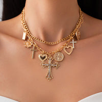 Thumbnail for A gold-toned layered necklace with rhinestone inlaid cross and heart pendants, displayed on a model mannequin.