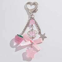 Thumbnail for A heart-shaped keychain with a bowknot, strawberry, and star charms, in pink tones with metal accents.